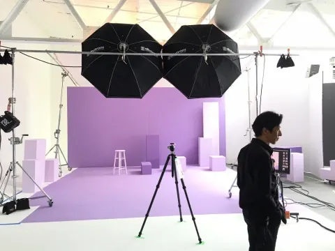 A studio setup with overhead lighting and a purple backdrop.