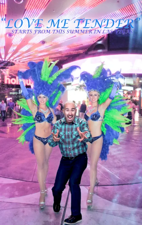 A man standing between two performers in colourful feathered costumes.