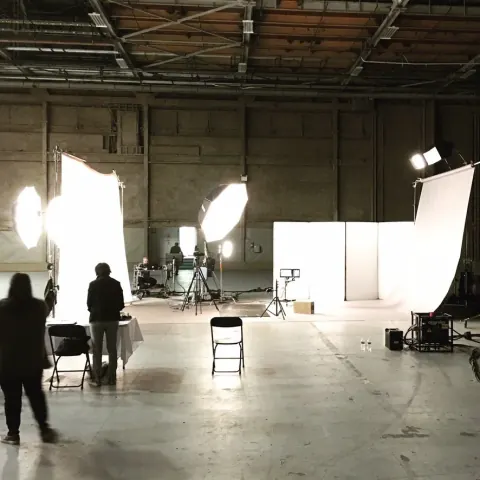 A large production studio with a crew and illuminated diffusion panels.