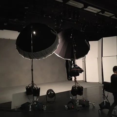 A dark studio containing large overhead softboxes and equipment.