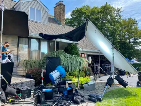A photographic lighting setup beside a house and garden.