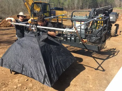 A crew using a long camera rig beside construction equipment.