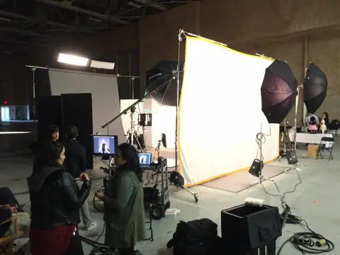A crew beside a large illuminated diffusion panel in a studio.