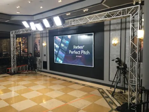 A production set with a large screen reading Forbes Perfect Pitch.