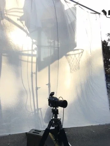 A camera silhouetted against a large translucent lighting screen.