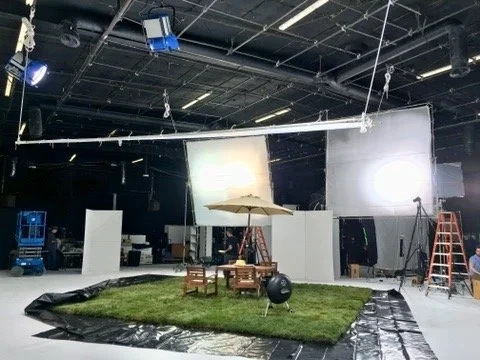 A studio set with overhead lights and a patch of artificial grass.