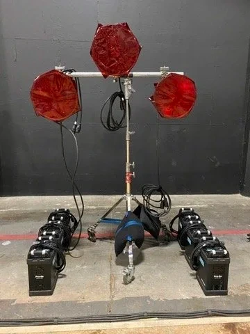 Three red lamps and other lighting equipment arranged against a dark backdrop.