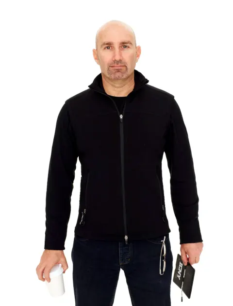 A man in a black zip-up top standing against a white backdrop.