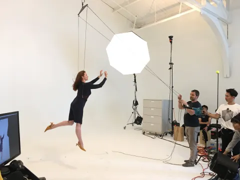 A woman jumping on a white studio set while a crew watches.