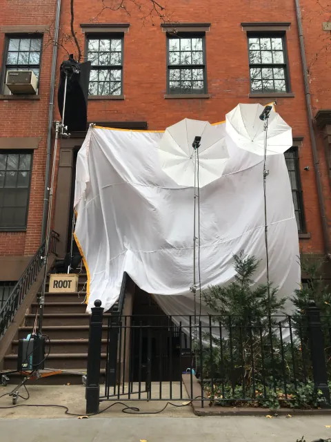 A large white diffusion screen mounted outside a brick building.