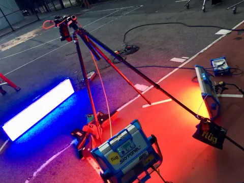 Coloured lighting tubes and stands casting blue and red light on a studio floor.