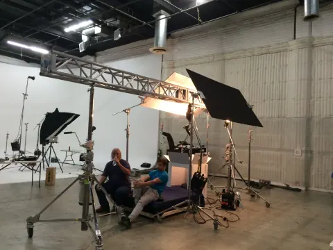 People seated beneath large lights on a studio set.