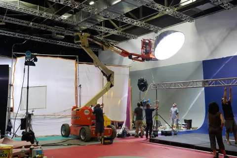 An elevated light and crew on a colourful studio set.