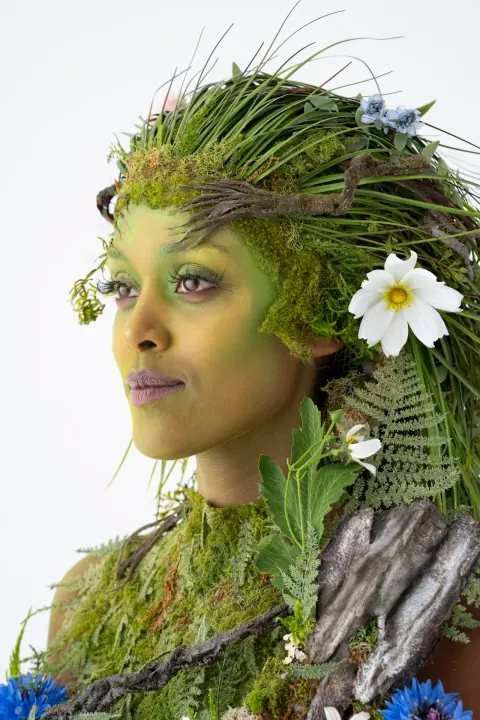 A side portrait of a person wearing a grass and flower headdress.