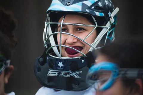 Close-up of a lacrosse player wearing a blue helmet and red mouthguard.