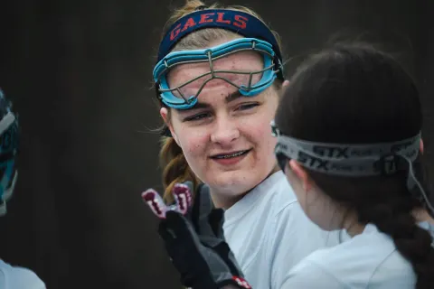 Two lacrosse players facing one another during a game.