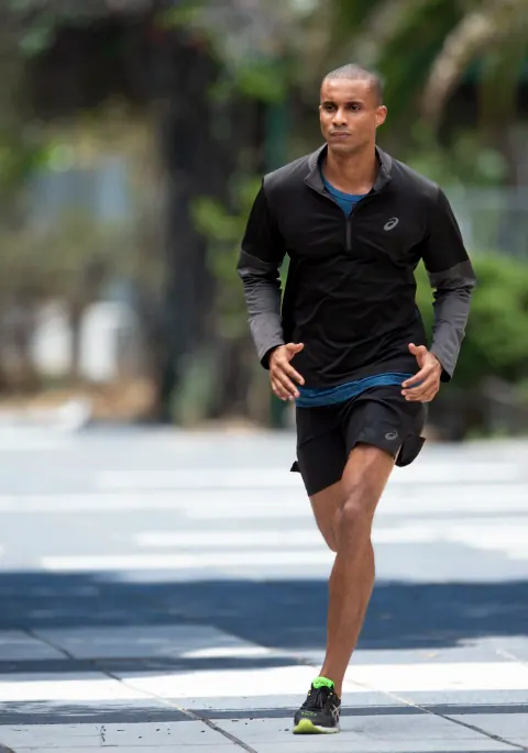 A man in black running along a city street.