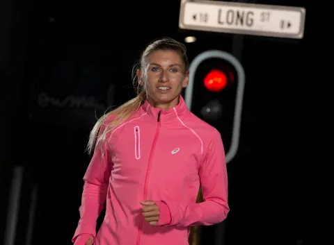 A woman in a pink zip-up sports top beside a Long Street sign.