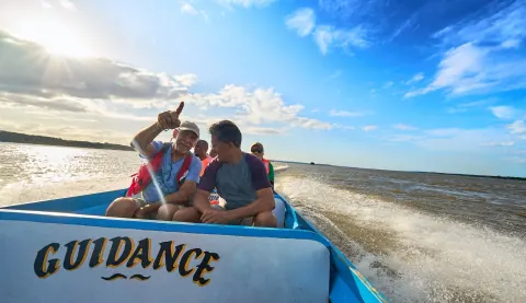 Passengers riding in a small motorboat marked Guidance.