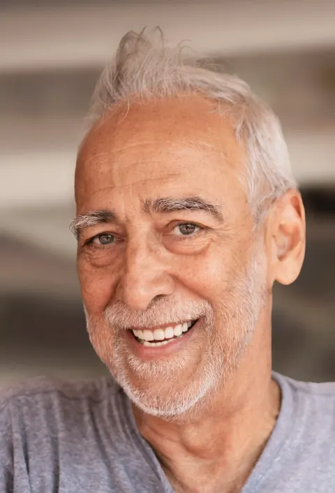 Close portrait of a smiling grey-haired man.