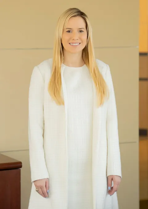 A smiling woman in a white outfit in an office interior.