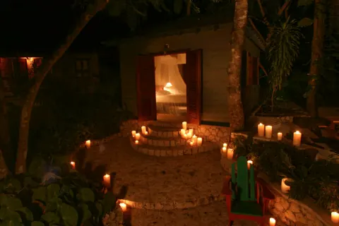 A candlelit path leading to a doorway among trees.