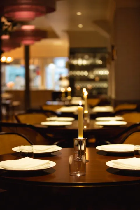 A restaurant table set with plates, wine glasses and candles.