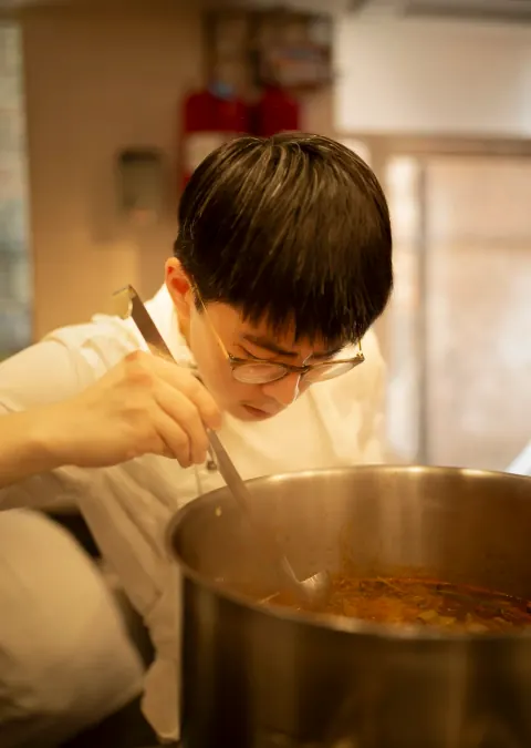 A chef stirring a large metal pot.