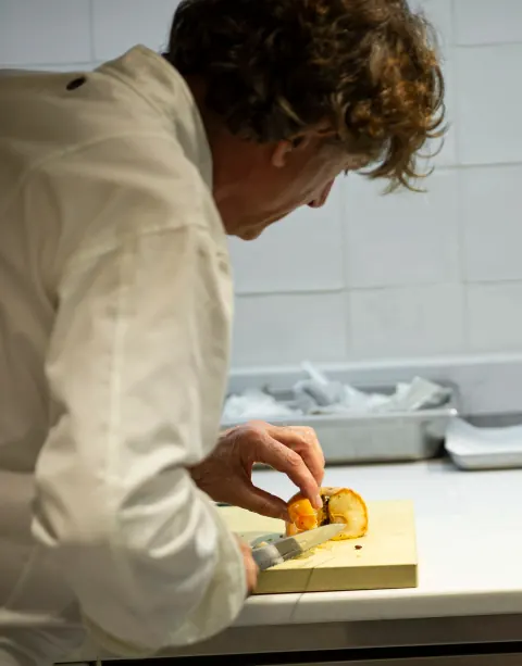 A chef arranging food on a preparation board.