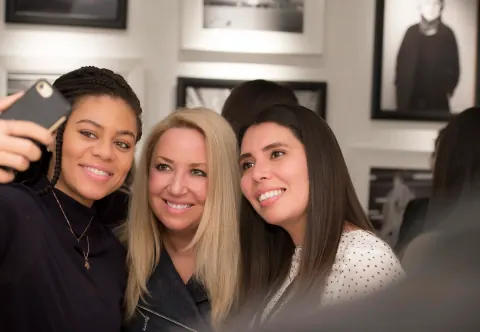 Three women posing together for a selfie at an event.