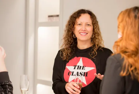 A smiling guest in a graphic black top talking with another guest.