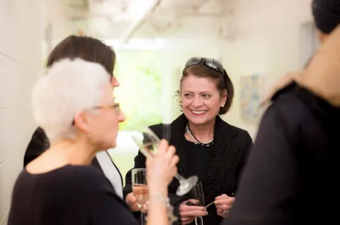 Guests talking together with drinks in a bright room.