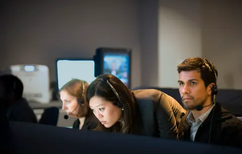 A group concentrating on monitors at a production desk.