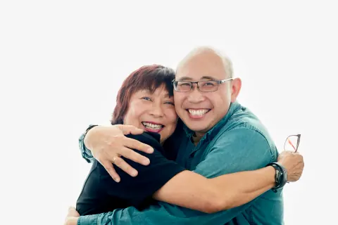 Two smiling people embracing against a white backdrop.