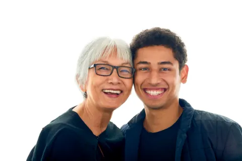 A woman with glasses and a young man smiling together.