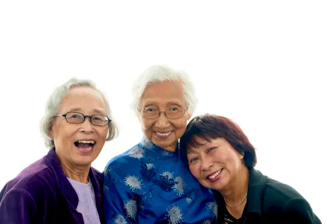 Three people laughing together against a white backdrop.