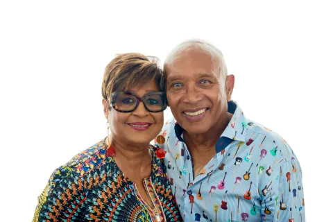 A smiling couple wearing colourful patterned shirts.