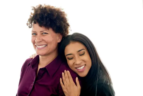 Two women embracing, one resting her head on the other’s shoulder.