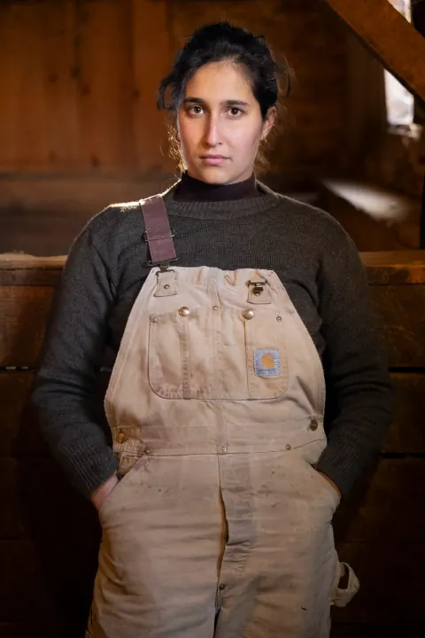 A person wearing a brown apron over a dark top.