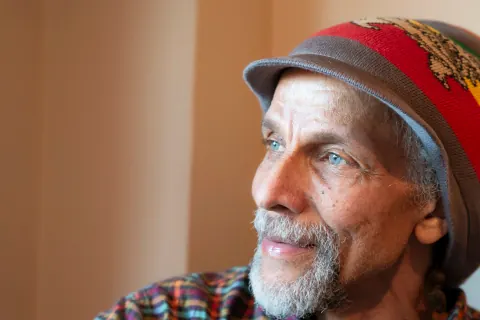 A bearded man in a colourful knit hat looking to the side.