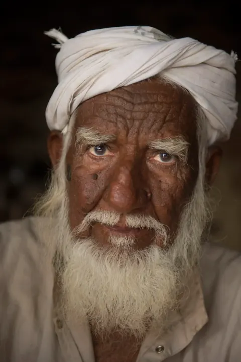 Close portrait of a white-bearded man wearing a white turban.