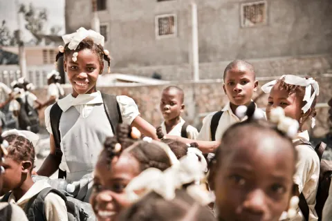 A group of children in school uniforms gathered outside a building.