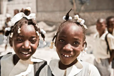 Two smiling schoolgirls standing close together.