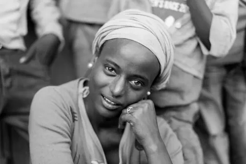 A monochrome portrait of a smiling woman resting her cheek on one hand.