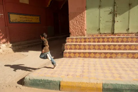 A child running beside a building with patterned tiled steps.