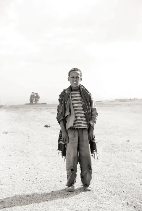 A monochrome portrait of a man in a jacket and striped scarf outdoors.